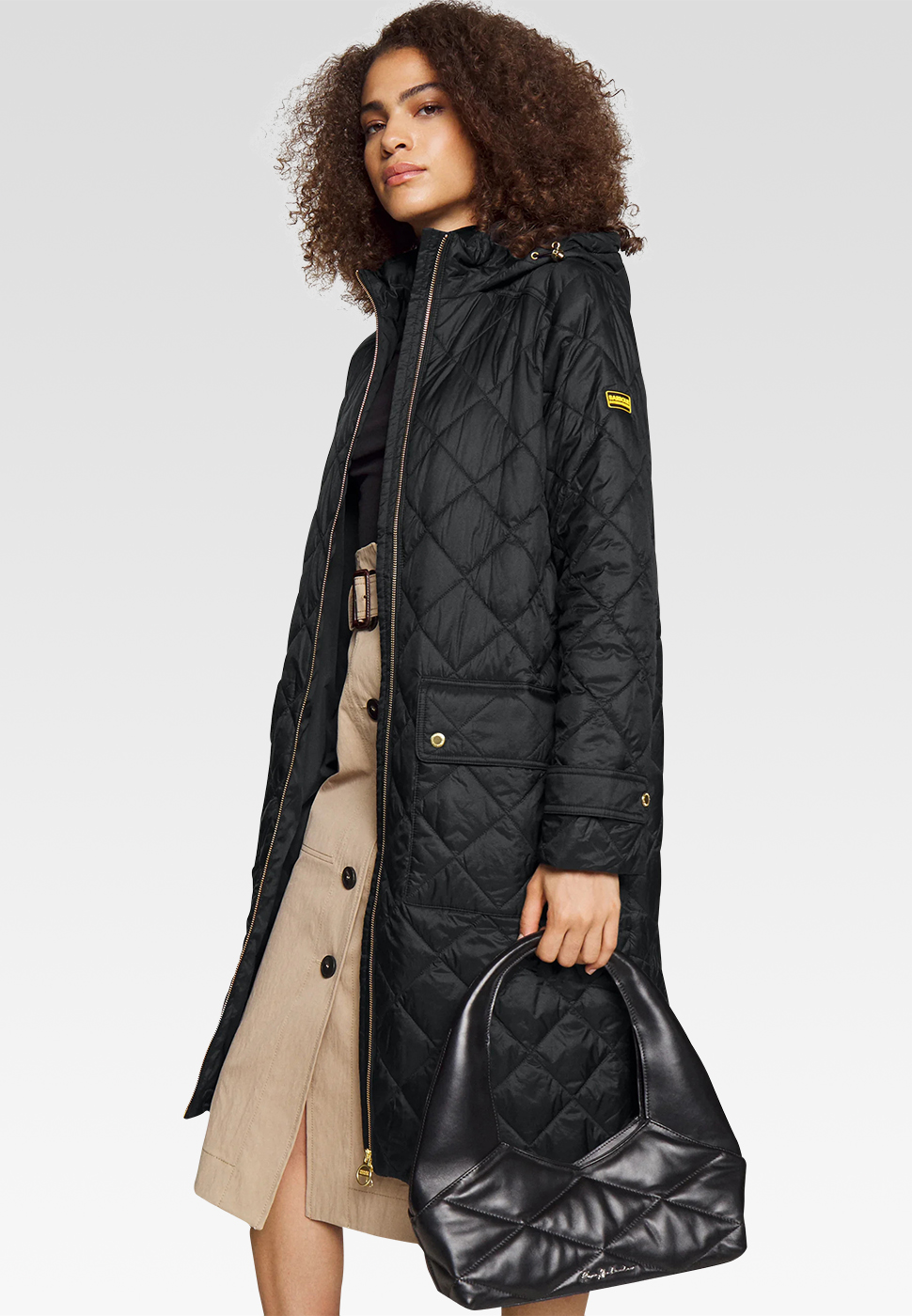 A lady with curly hair in a long black winter jacket